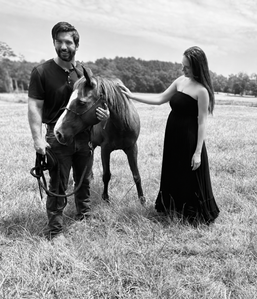 The broker and his wife standing with a horse in a field
