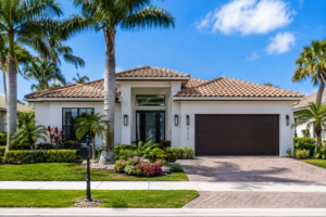 Single-story Florida home with palm trees, a paver driveway and a two-car garage