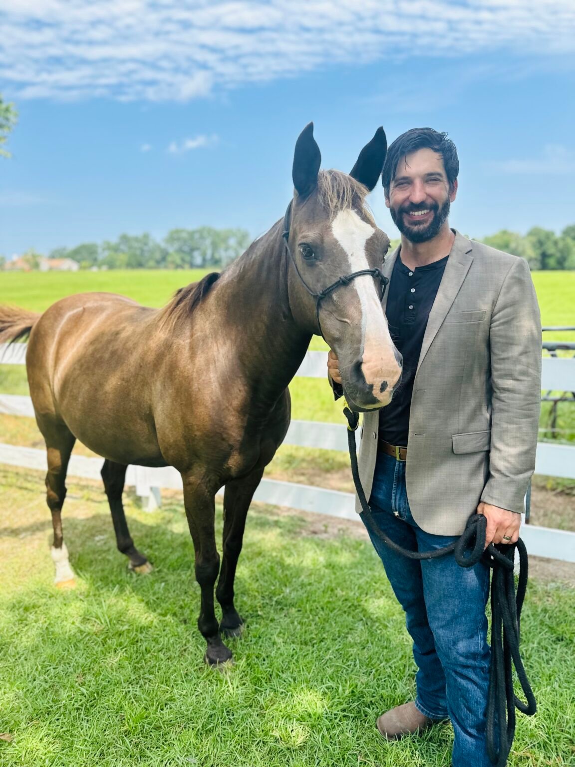 The broker standing with his horse in a pasture