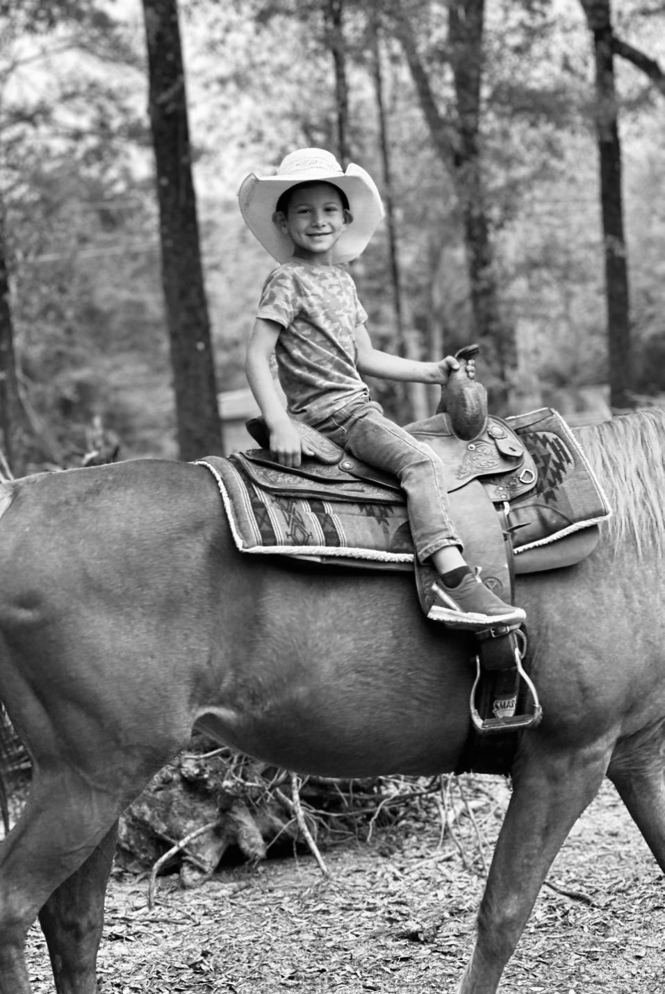 A child in a cowboy hat riding in the saddle