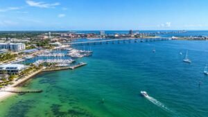 Aerial view of a bayfront marina, boats and a long bridge under a blue sky